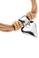 Pulsera con múltiples tiras de hilo efecto seda color beige claro, anudadas a los extremos con cuero del mismo tono. Presenta un dije central metálico plateado con forma de corazón estilizado. El cierre es de mosquetón de acero inoxidable.