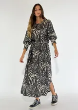 Vestido largo con estampado abstracto en blanco y negro, corte holgado, mangas 3/4 abullonadas y cinturón fino a tono.