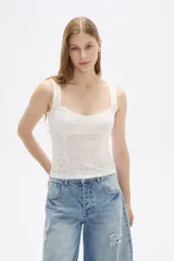 Top sin mangas confeccionado en algodón con diseño de broderie, corte al cuerpo y escote redondo con detalle de puntilla en los bordes.