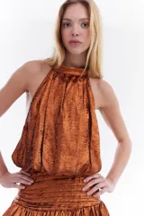 Top metalizado color cobre, con cuello halter y diseño balloon con caída fluida.