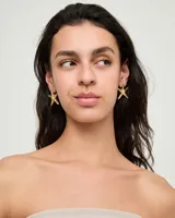 Aros tipo caravanas con diseño de estrella de mar, bañados en oro 18k con acabado brillante.