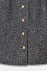 Blazer de corte entallado con cuello redondo, manga larga y hombreras. Presenta cierre frontal con botones dorados y una textura sutil en la tela.