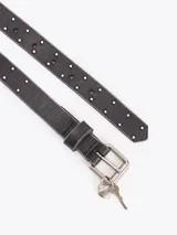 Cinturón de cuero vacuno negro con efecto gastado, adornado con mini tachas metálicas a lo largo de la lonja, hebilla metálica y dijes colgantes en forma de llave.