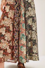 Falda larga plisada con diseño patchwork de diferentes estampados florales y abstractos en tonos otoñales y oscuros, con detalles metalizados. El forro es de poliéster.