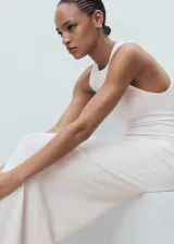 Vestido largo de punto color blanco, de corte entallado, con cuello halter y sin mangas.