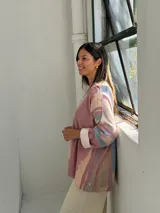 Sweater de punto con diseño abstracto en tonos rosados, beige y azul, de corte holgado, cuello en V y mangas largas con puños vueltos.