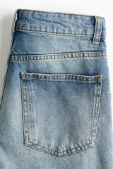 Jean de cinco bolsillos en denim de algodón rígido, con piernas maxivolumen de diseño curvo y corte estándar de cadera a muslo, ligeramente ceñidas en el bajo mediante trabilla. Cuenta con cintura de tiro alto, cierre y botón.