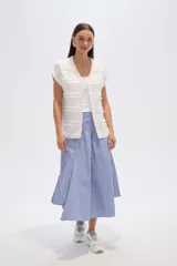 Poncho color marfil con diseño de flecos horizontales y cuello redondo.