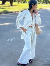 Camisa larga tipo sobrecamisa o abrigo ligero, color verde menta pálido con estampado floral en tono amarillo claro. Presenta escote en V con atado frontal mediante lazos, mangas largas con detalle fruncido y puños con flecos en tono turquesa.