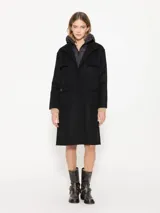 Tapado negro de paño con chaleco interno desmontable con cierre en el cuello. Tiene acceso mediante botones y bolsillos plaque en el delantero.