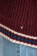 Cardigan de punto color bordó con diseño oversize, cuello en V y cierre frontal con botones. Presenta detalles de rayas en contraste en color crema y azul en los bordes, puños y ruedo, además de dos bolsillos frontales aplicados.