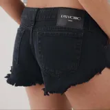 Short de denim negro de tiro bajo, con bordes desmechados y bolsillos delanteros y traseros.
