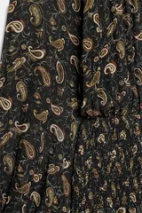 Vestido corto de cuello subido y manga larga con puños elásticos. Presenta cintura elástica con detalle de nido de abeja, abertura frontal y trasera, y bajo con volantes. Cierre posterior con botones.