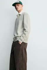 Sudadera de manga larga estilo polo con diseño de rayas horizontales anchas en azul marino y blanco. Presenta cuello de solapa en contraste, cierre frontal con botones ocultos y acabados en rib en puños y bajo.