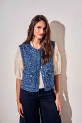 Chaleco capitoneado de jean azul con bordados florales en tono oscuro, cuello redondo y bolsillos delanteros aplicados con solapa fruncida.