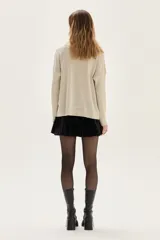 Sweater de tejido de punto con acabado brillante de lurex, escote en V y mangas largas. Presenta detalles de bordados florales en los hombros y un diseño con tajos laterales en el ruedo.