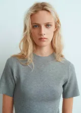 Vestido corto gris de tejido de punto fino, con cuello perkins y mangas cortas. Presenta un diseño evasé y sin cierre.