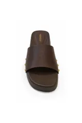 Sandalias tipo zueco marca Paddock, color marrón, con suela plana de plataforma baja, tira ancha en el empeine decorada con tachas doradas laterales.