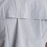 Camisa de manga corta Merrell, color gris, con cuello clásico y cierre frontal de botones. Presenta dos bolsillos frontales con solapa y logo de la marca estampado en el pecho.