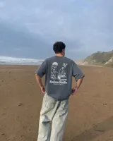 Remera oversize negra con diseño gráfico en la espalda que incluye la inscripción "Kaboa Radio" y un personaje ilustrado, de corte amplio y mangas cortas.