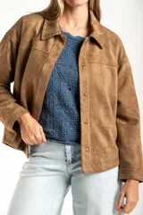Sobrecamisa de gamuza sintética color camel, con corte oversize, cuello clásico con detalle de costura, cierre frontal con botones metálicos y mangas largas.