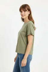 Remera blanca de algodón, de corte ajustado, con cuello redondo y mangas cortas terminadas con volados delicados.