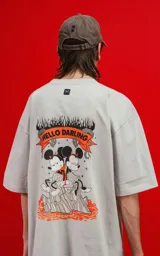 Remera de algodón premium color gris claro, corte oversize, con cuello redondo y manga corta. Presenta un estampado frontal pequeño con dos personajes de Disney (Mickey y Minnie) en llamas con el texto "THE FLAME OF LOVE".