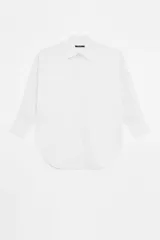 Camisa blanca de poplin de algodón, manga larga con puños anchos y acceso por botones en cartera central y puños.