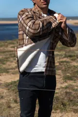 Camisa leñadora marrón a cuadros con forro de corderito sintético, cierre con botones y dos bolsillos frontales con tapa.
