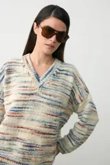 Sweater de punto con diseño oversize y cuello en V, tejido en tonos crudo con rayas horizontales multicolores.