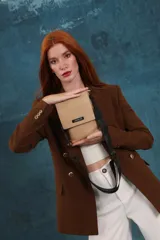 Phonebag pequeña color mostaza, confeccionada en cuero sintético, con solapa frontal y correa ajustable con logo de la marca.