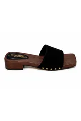 Zueco de inspiración artesanal marca Daniel Cassin, con base efecto madera y taco bajo. Presenta una capellada ancha de color negro con detalles de tachas metálicas doradas en los laterales.