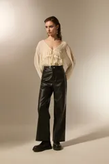 Pantalon de corte recto confeccionado en eco-cuero negro, con tiro medio y costuras horizontales a la altura de la rodilla.
