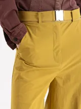 Pantalón de corte ancho y silueta relajada, confeccionado en tejido técnico con elasticidad. Presenta recortes verticales en el frente que terminan en aberturas en el ruedo y cuenta con un cinturón integrado con hebilla metálica de enganche.