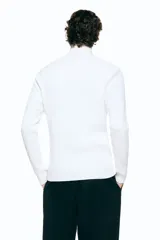 Saco de punto acanalado en mezcla de algodón y viscosa, con cuello elevado, cierre frontal bidireccional y mangas tipo martillo. Presenta un corte ajustado que define la silueta.