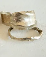 Brazalete rígido plateado con textura irregular.