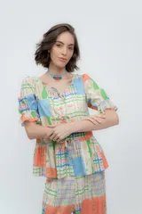 Camisa estampada con flores, de lino o popelina, con cuello en V y mangas cortas con volados. Se cierra con lazos en el frente.