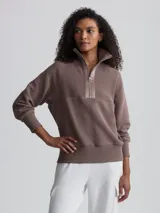 Buzo color marrón topo de tejido acanalado con cierre de cremallera metálica y cuello alto.