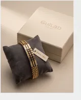 Pulsera de acero con baño de oro, compuesta por una cadena de eslabones trenzados y una placa central rígida con diseño geométrico de cuadros en tonos dorados y negros.