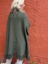 Capa estilo ruana verde militar con flecos en el ruedo y diseño abierto.