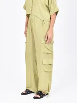 Pantalón cargo ancho de color verde oliva claro, con cintura elástica y bolsillos tipo parche a los lados de las piernas.