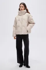 Campera puffer de cuello alto con capucha integrada, cierre frontal y diseño acolchado con costuras onduladas. Presenta mangas largas y bolsillos laterales.