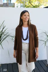 Saco abierto tipo cárdigan de punto en color chocolate, con diseño de corte recto, mangas largas y bolsillos frontales aplicados.