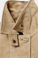 Chaqueta de ante color tostado con cuello solapa, manga larga con puño, bolsillos con solapa en el delantero y cierre frontal con botones.