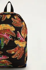 Mochila negra con estampado colorido de bananas, compartimento principal amplio, bolsillo frontal con cierre y correas ajustables.