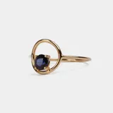 Anillo de oro 18k con diseño minimalista que presenta un zafiro azul engastado en un círculo abierto.