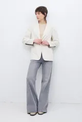 Blazer de corte sastrero en color crema, con solapas clásicas, cierre frontal de un botón y detalles de costuras decorativas en los puños.