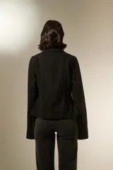 Sobrecamisa de jean color negro con cierre frontal, cuello clásico y detalle de cordones laterales ajustables con ojalillos metálicos.