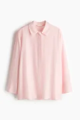 Camisa oversize de manga larga en mezcla de viscosa, color rosado claro. Cuenta con cuello camisero clásico, cierre frontal con botonadura oculta y canesú en la espalda. Presenta hombros caídos, puños anchos y bajo recto con aberturas laterales.