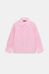 Camisa de cuello solapa y manga larga con puños abotonados. Presenta un diseño de rayas verticales con un estampado floral lineal superpuesto. Cierre frontal con botones.